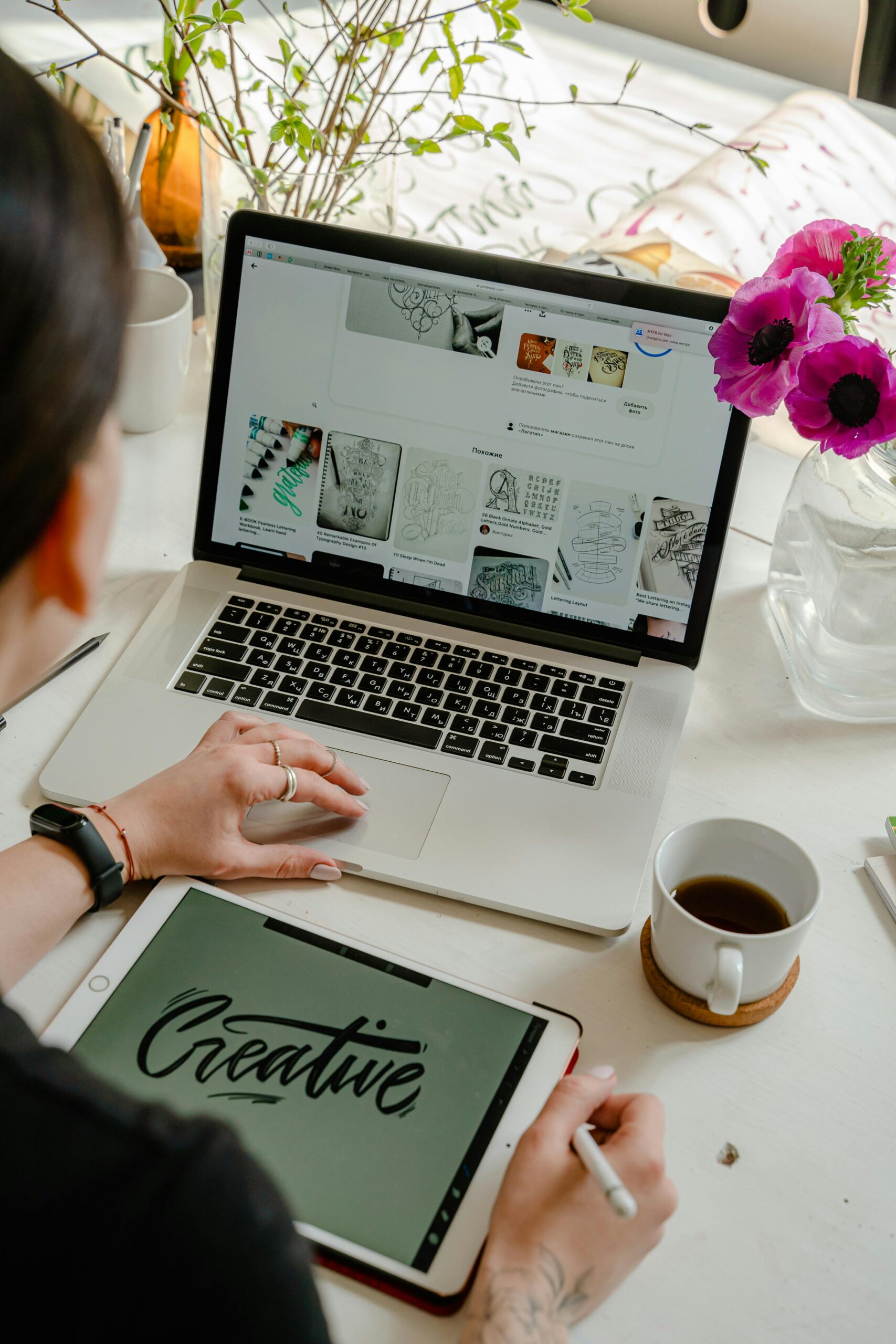 Woman scrolling on her laptop and drawing on her tablet.
